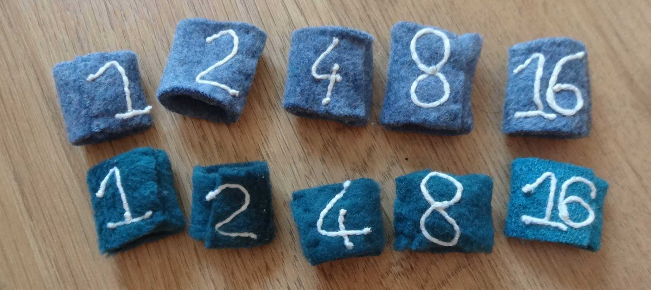une photo de bagues en feutrine, numérotées 1,2,4,8,16